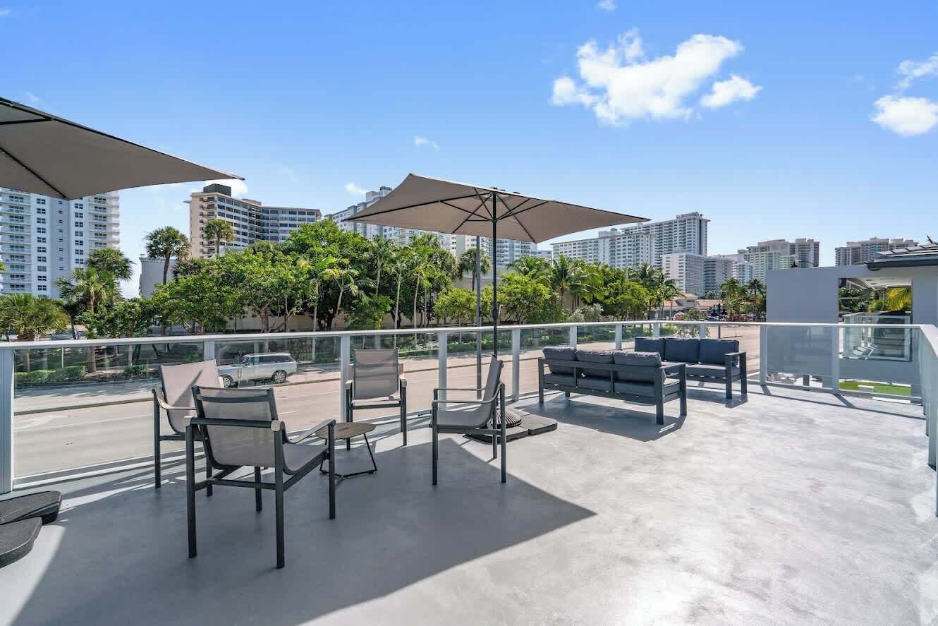 A rooftop terrace with outdoor seating, umbrellas, and a view of city buildings.