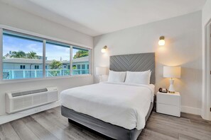 Ein Schlafzimmer mit einem Bett, Nachttischlampen, einem Nachttisch, einem Fenster und einem Wandheizkörper.