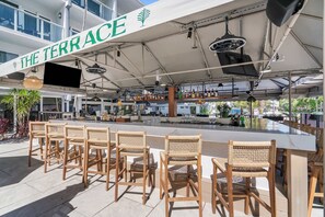 Eine Straßenterrasse mit Barbereich, Korbstühlen und einem Schild mit der Aufschrift 'THE TERRACE'.