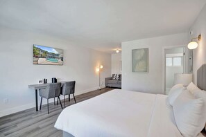 Ein modernes Hotelzimmer mit Bett, Schreibtisch, Stühlen und einem Gemälde eines Pools.