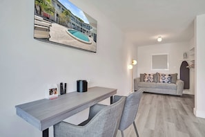 Ein modernes Wohnzimmer mit einem grauen Sofa, einem Couchtisch und einem an der Wand befestigten Fernseher.