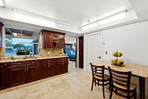 Una cocina con encimera de granito, armarios de madera y una zona de comedor con dos sillas.