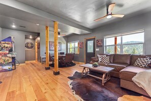 Ein modernes Wohnzimmer mit Holzboden, einer braunen Ledersofa, einem Couchtisch und einem Deckenventilator.