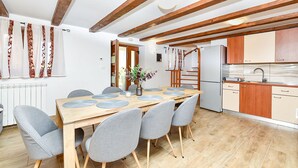 Una cucina moderna con travi in legno, un'area pranzo con tavolo in legno e sedie grigie, e un frigorifero.