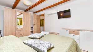 Una camera da letto con un letto, due cuscini, una TV, un armadio e un termosifone.