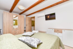 A bedroom with a bed, two pillows, a TV, a wardrobe, and a radiator. - House 2442/251993 (Istria - Vodnjan), 8000m from the beach (Vodnjan)