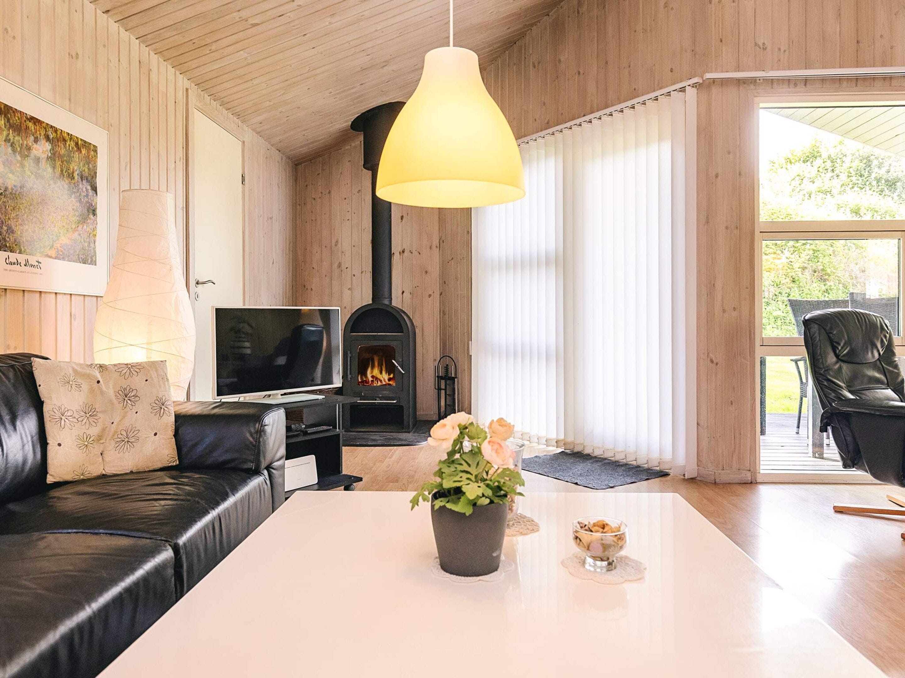 A cozy living room with a fireplace, a sofa, a coffee table with flowers, and a television.