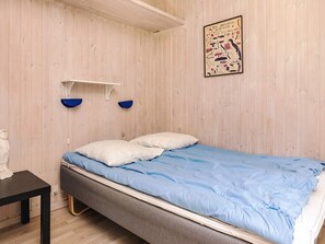 A room with a bed, a small table, and a wall-mounted shelf. - 10 Person Holiday Home in Rudkobing (Rudkobing)