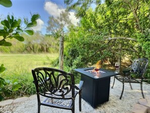Un espace extérieur aménagé avec une table et des chaises, entouré de verdure et d’arbres.