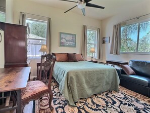 Une chambre à coucher comprenant un lit, un bureau, une chaise, un canapé et un ventilateur de plafond.