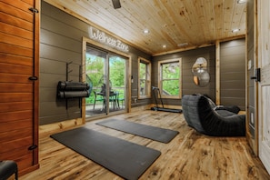 Une salle de bien-être dotée d’un plancher en bois, d’un tapis de yoga, d’un fauteuil de massage et d’un tapis de course.
