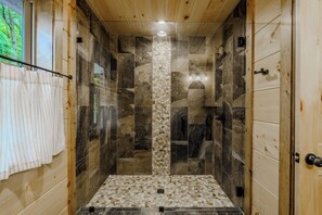 Een douche met stenen tegels en een houten plafond.