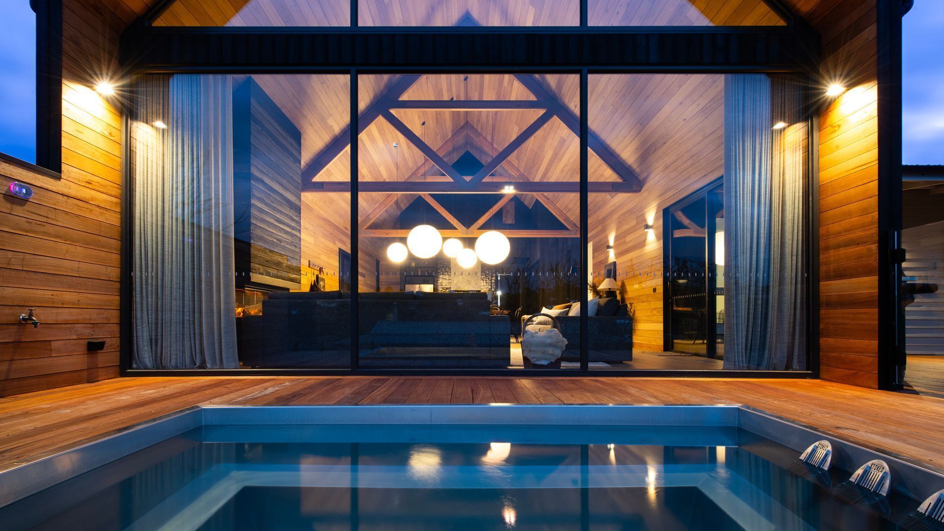 Ein modernes Haus mit Swimmingpool, Holzfassade und großen Fenstern.
