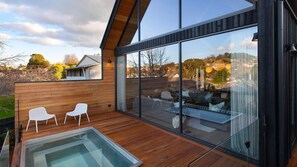A modern house with a large glass window, wooden deck, and a hot tub. - Margaux - Sophisticated luxury (Daylesford)