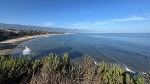Un paysage côtier avec une plage, l’océan et des montagnes à l’horizon.