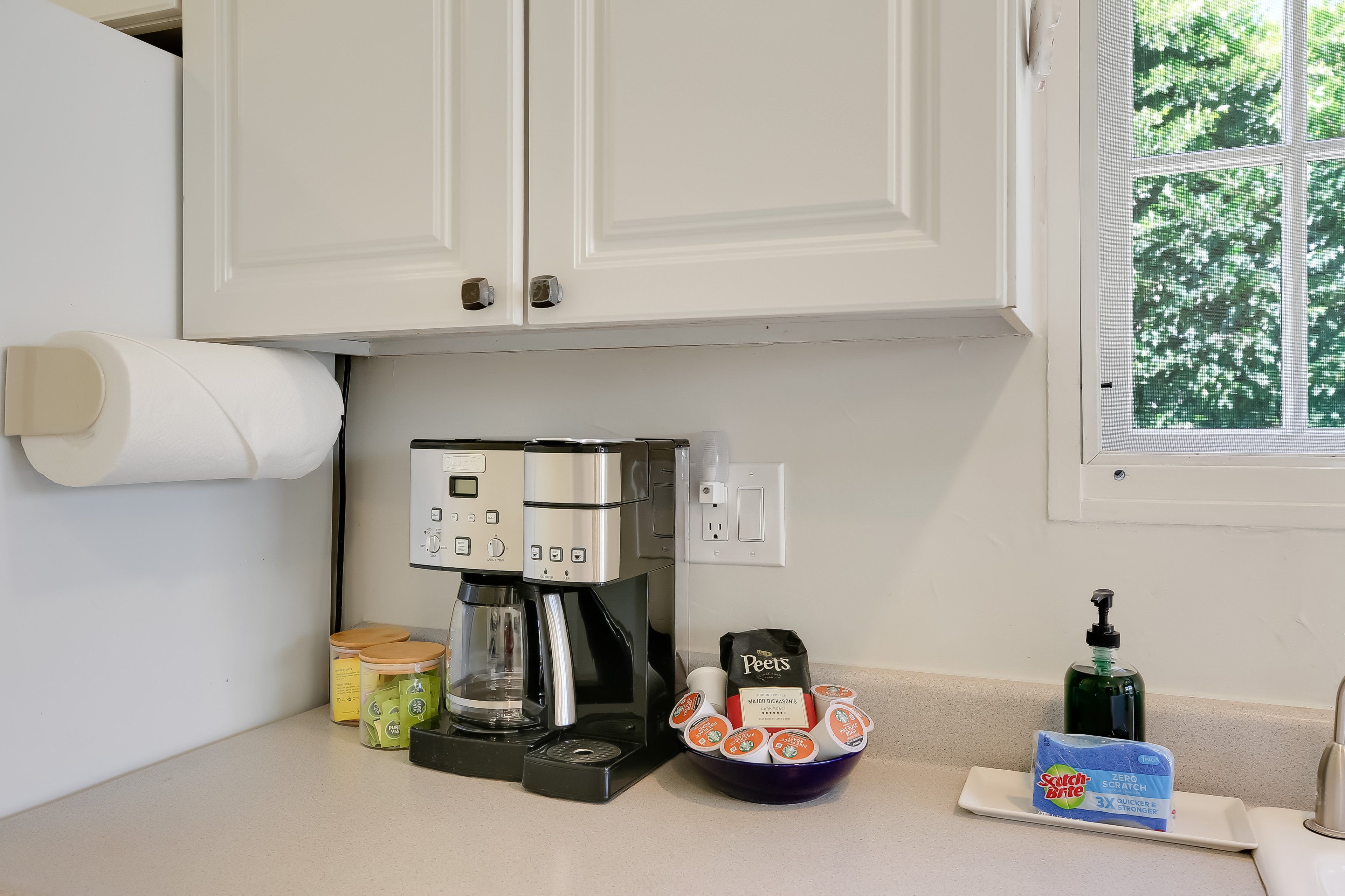 A kitchen with a coffee maker, a Peet's coffee bag, a bottle of dish soap, and a box of Scotch-Brite Zero Scrub.