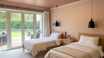 Ein Schlafzimmer mit zwei Betten, einer großen Schiebetür und Blick auf einen Garten.