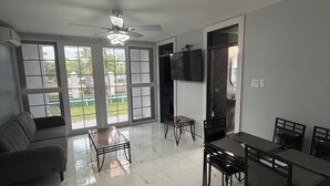 A spacious living area with a sofa, dining table, chairs, and a TV mounted on the wall. - Luxury 2 bed 2 bath at Sandcastle Ocho rios (Ocho Rios)