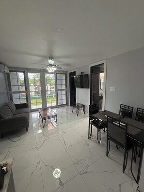 A spacious living area with a sofa, dining table, chairs, and a TV mounted on the wall. - Luxury 2 bed 2 bath at Sandcastle Ocho rios (Ocho Rios)