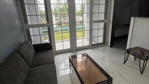 A living room with a sofa, a glass-top coffee table, and a TV stand. - Luxury 2 bed 2 bath at Sandcastle Ocho rios (Ocho Rios)
