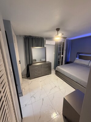 A bedroom with a bed, dresser, mirror, air conditioning unit, and a ceiling fan. - Luxury 2 bed 2 bath at Sandcastle Ocho rios (Ocho Rios)