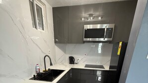 A modern kitchen with a sink, stove, microwave, and cabinets. - Luxury 2 bed 2 bath at Sandcastle Ocho rios (Ocho Rios)