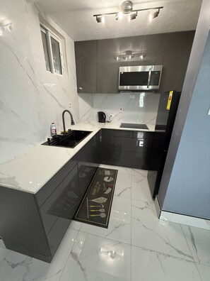 A modern kitchen with a sink, stove, microwave, and cabinets. - Luxury 2 bed 2 bath at Sandcastle Ocho rios (Ocho Rios)