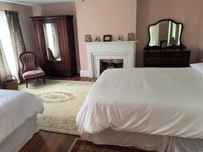 Una camera da letto con due letti, un camino, uno specchio e una sedia.