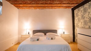 Een hotelkamer met een bed, twee nachtkastjes, een kaptafel en een plafond van baksteen.