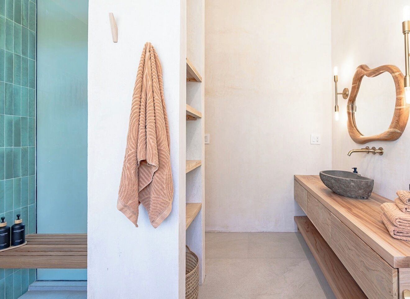 A bathroom with a wooden vanity, a stone basin, a towel rack, and a mirror with a wooden frame.