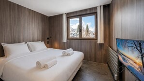 A bedroom with a bed, a window with a view of mountains, and a painting on the wall. - L'Écrin des Cristaux avec balcon - Welkeys (Megève)