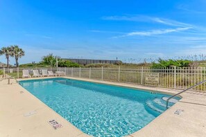 A clear swimming pool with a shallow end, a lifeguard station, and a fenced area with lounge chairs. - 3BR Oceanfront Condo | Pool | Main Street (North Myrtle Beach)
