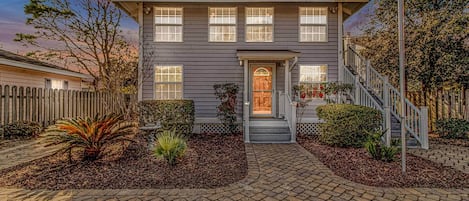 A two-story house with a front porch, a staircase, and a well-maintained garden.