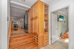 Un couloir avec des armoires en bois, un coin cuisine à l’arrière-plan et une porte donnant sur une autre pièce.