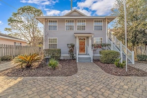 A two-story house with a front porch, a staircase, and a brick driveway. - 7BR Family Oasis | Heated Pool + Walk to Beach (North Myrtle Beach)