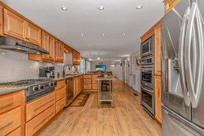 A modern kitchen with wooden cabinets, stainless steel appliances, and a central island. - 7BR Family Oasis | Heated Pool + Walk to Beach (North Myrtle Beach)