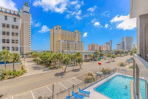 A hotel with a pool, a parking lot, and a view of the city skyline. - Updated 3BR w/ Oceanviews on MB Boardwalk! (Myrtle Beach)