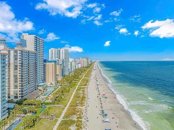 A coastal cityscape with high-rise buildings, a beach, and a clear blue sky. - Updated 3BR w/ Oceanviews on MB Boardwalk! (Myrtle Beach)