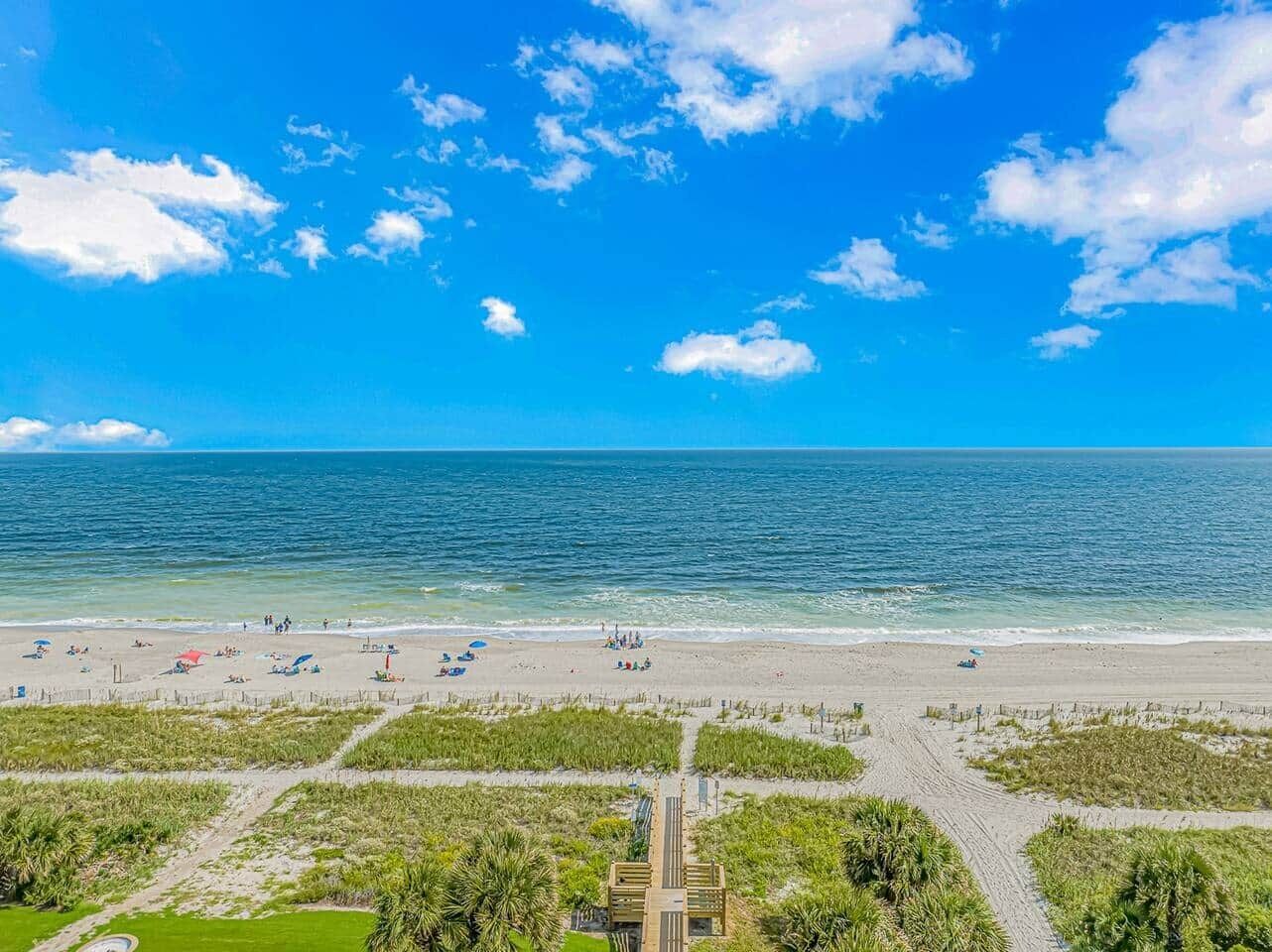A beach with a clear sky, a sandy shore, and a few umbrellas.