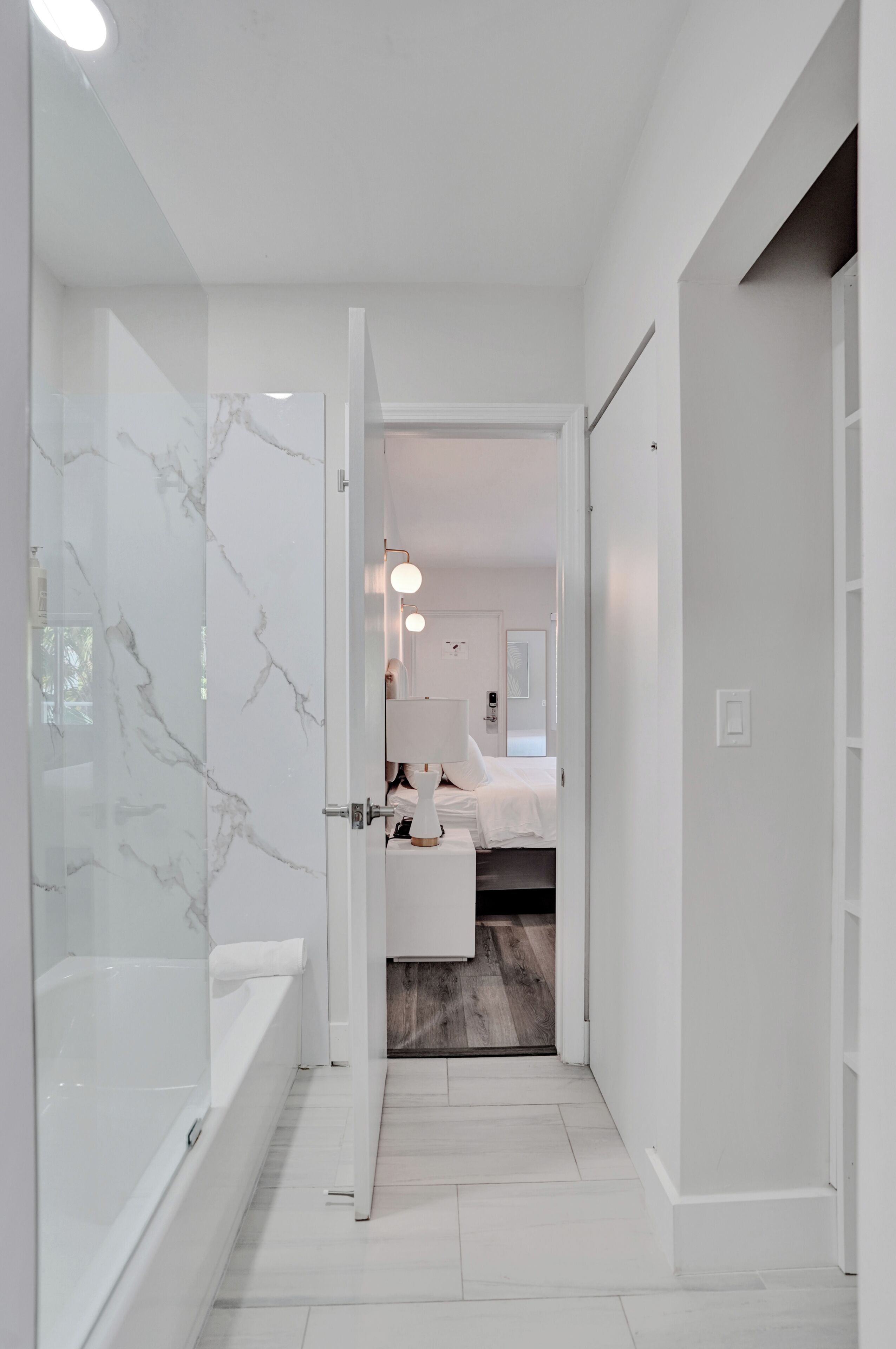 Ein modernes Badezimmer mit einer Duschkabine aus Glas, einer weißen Badewanne und Holzboden.