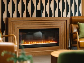 A modern living room with a fireplace, wooden furniture, and a patterned wall. - Independent Boutique Hotel Near Bentonville's Top Sights (Bentonville)
