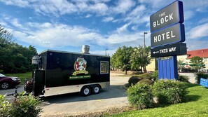 Un camión de comida con un cartel que dice 'The Block Hotel' y una flecha indicando la izquierda.