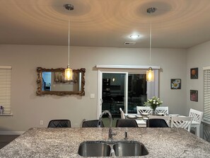 A kitchen with granite countertops, a double sink, pendant lights, and a dining area with chairs and a table. - Spacious 4BR Family Retreat Near Whitewater & Airport, pets allow (Charlotte)
