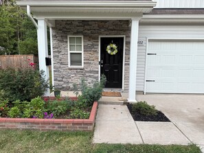 A house with a stone facade, a black front door, a white garage door, and a mailbox. - Spacious 4BR Family Retreat Near Whitewater & Airport, pets allow (Charlotte)