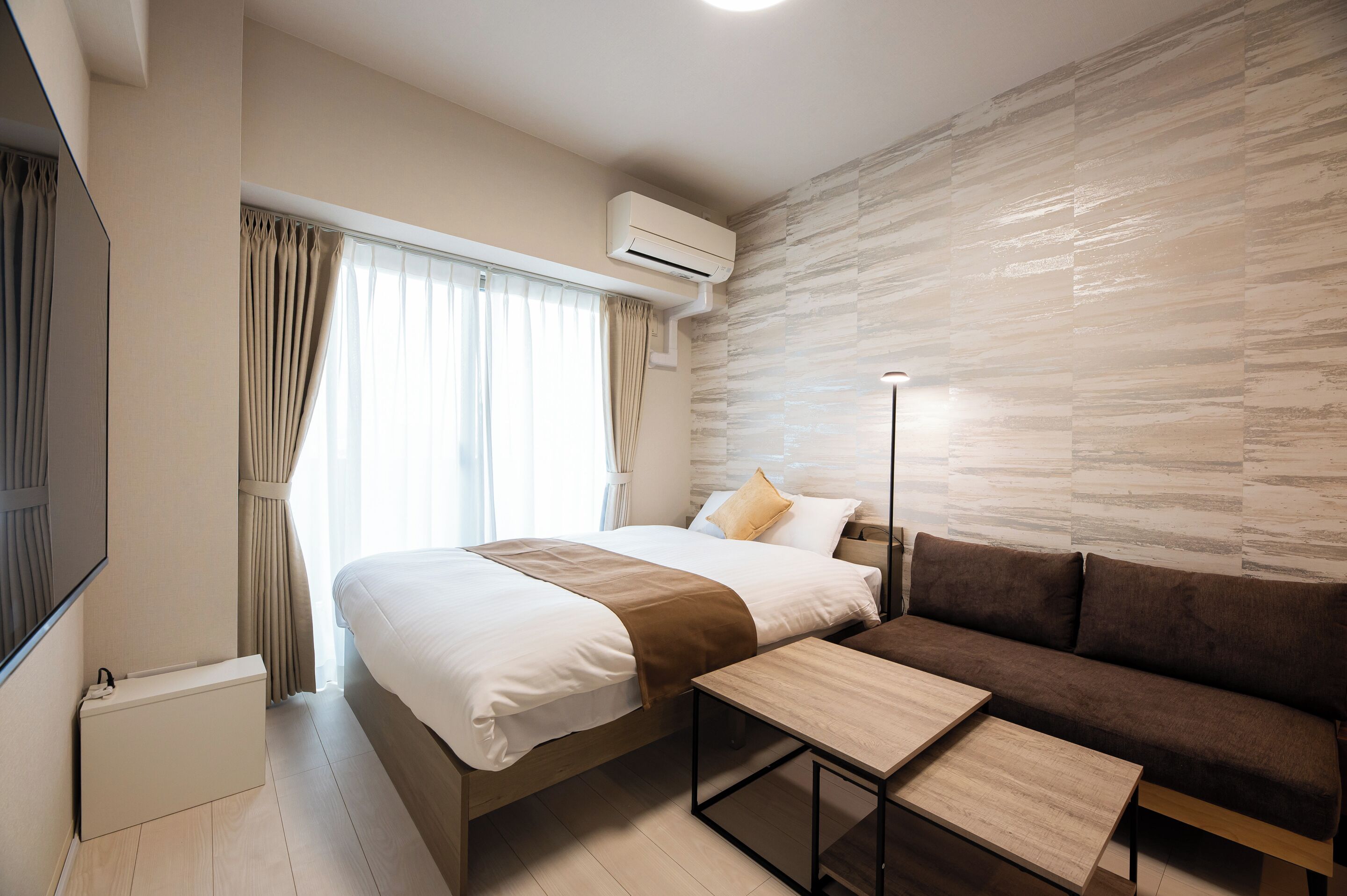Une chambre d’hôtel moderne équipée d’un lit, d’un canapé, d’une petite table et d’un appareil de climatisation.