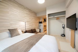 A modern hotel room with a large bed, a wardrobe, a television, and a desk with a lamp. - ESTRELA Ogusu (Fukuoka City Minami ku)