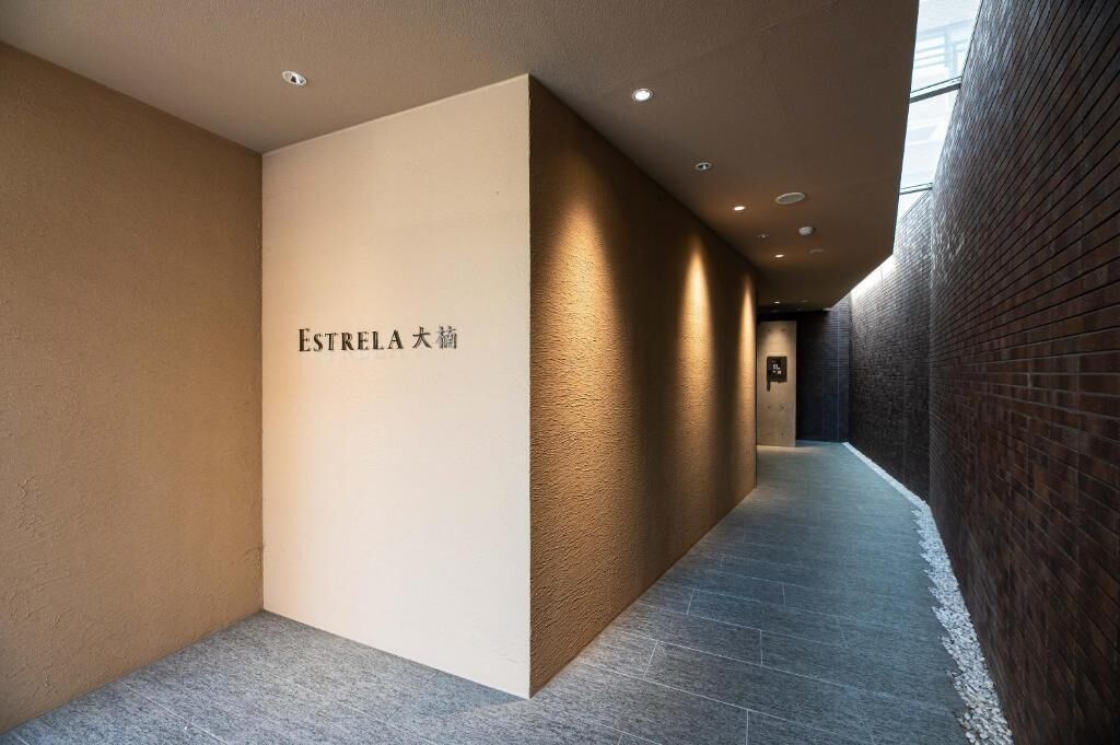 A corridor with a textured wall on the left and a brick wall on the right, with a sign reading 'ESTRELA 大綱'.