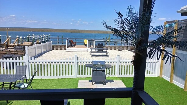 A patio with a grill, seating, and a view of the water.