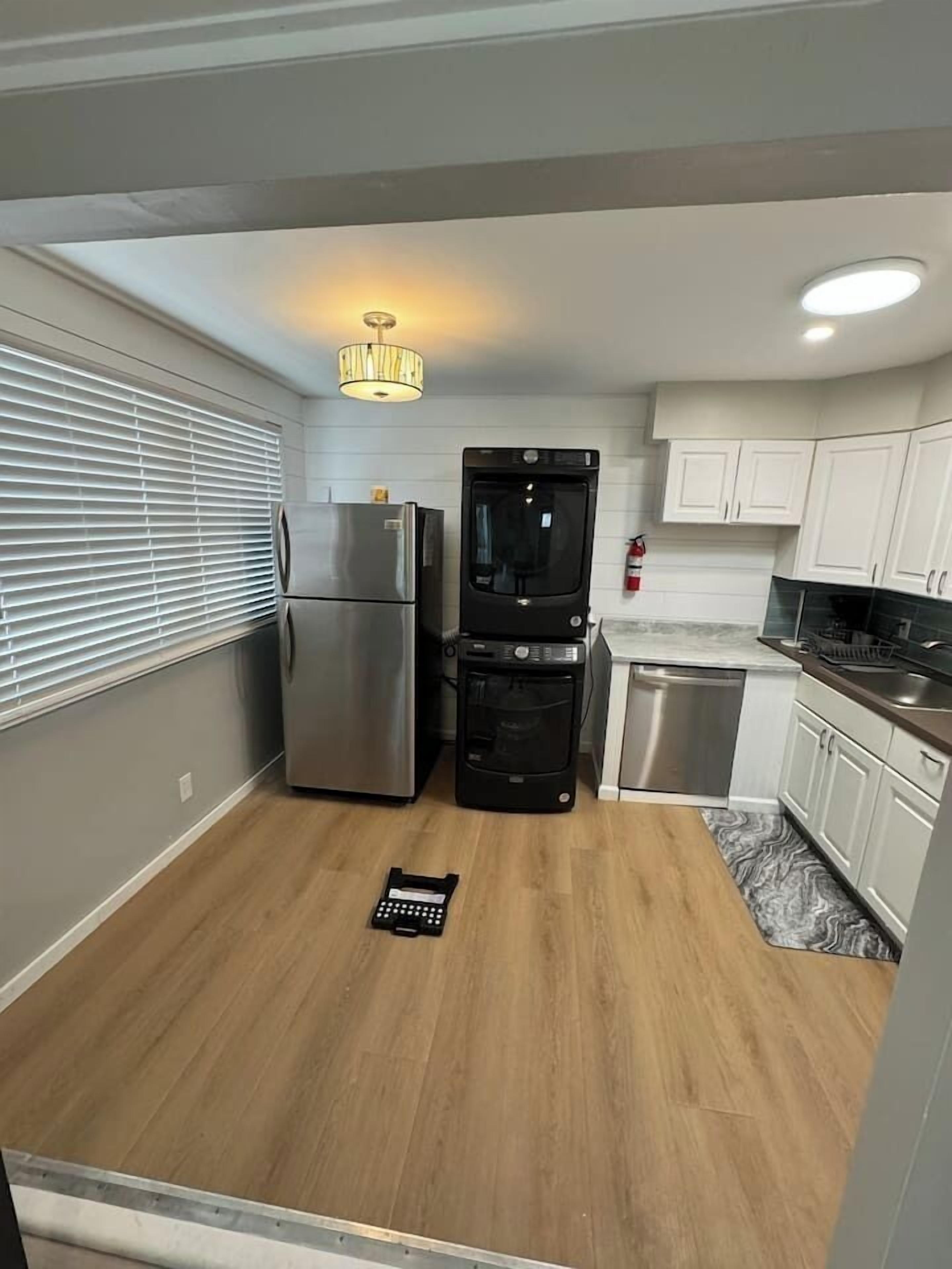 A compact kitchen with a refrigerator, oven, and dishwasher, a small countertop, and a ceiling light fixture.