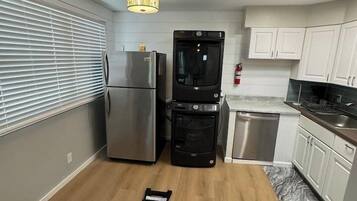 A compact kitchen with a refrigerator, oven, and dishwasher, a small countertop, and a ceiling light fixture.